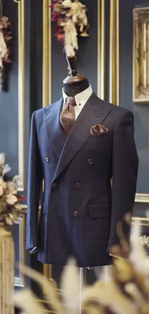 Navy blue double-breasted suit on a mannequin with an ornate decorative backdrop