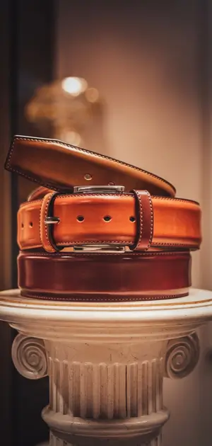 Stacked leather belts in shades of fall on column