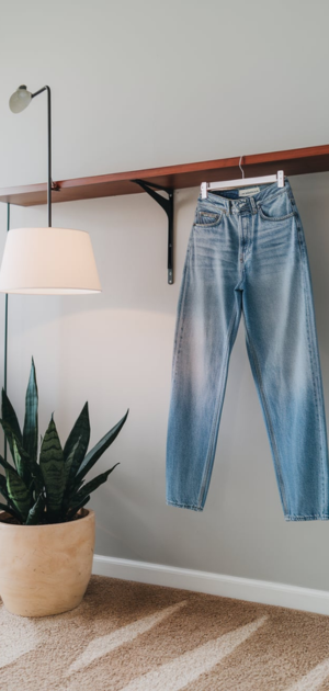 Distressed light blue jeans with a wooden board and modern lamp in the background
