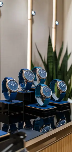 Blue wristwatches with metallic and leather straps displayed on a shelf.