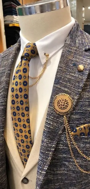Men’s sports suit paired with gold tie, lapel pin, and elegant chains.