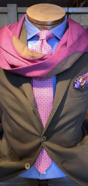 Travel accessories for long flights A brown suit with a pink tie, scarf, and pocket square for a polished look.
