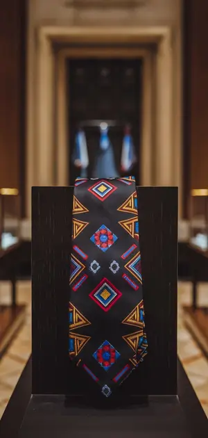 Dark blue tie with red geometric patterns on display
