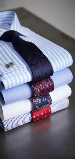 Folded casual fashion shirts for men stacked with sleek ties in vibrant designs.