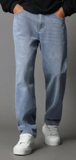 Relaxed-fit men's minimalist light-wash jeans paired with white sneakers.