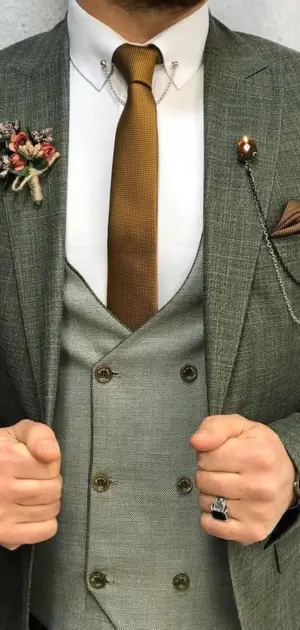 Men's wedding suit ideas: An elegant groom's wedding suit with a gold tie, boutonniere, pocket chain, and vest.