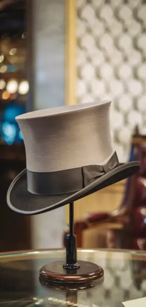Gray and black top hat displayed on glass table