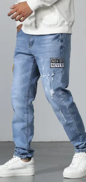 A man wearing relaxed-fit cotton jeans with graphic patches and ripped design.