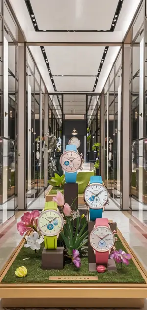 Colorful men's watches displayed in a spring-themed retail setting with flowers and grass