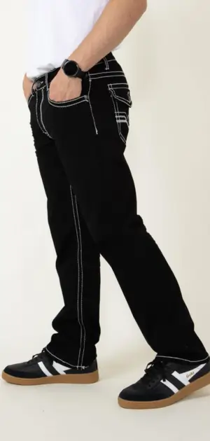 Man wearing black bootcut jeans with white stitching and men's bootcut jeans sneakers.