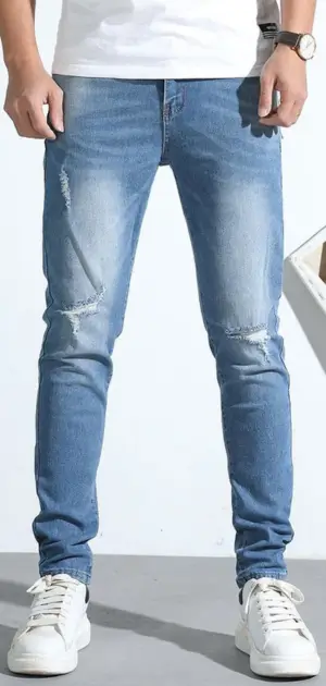 Mens all cotton jeans A man wearing slim-fit distressed cotton jeans, paired with casual sneakers.