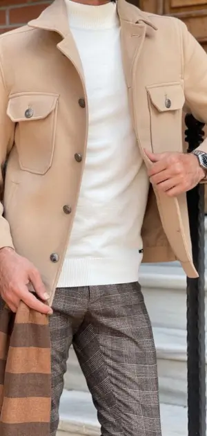 A beige neutral jacket styled with a white sweater, plaid trousers, and a striped scarf.