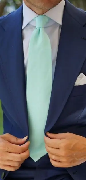 Pastel blue tie paired with a navy suit and pocket square for formal attire.