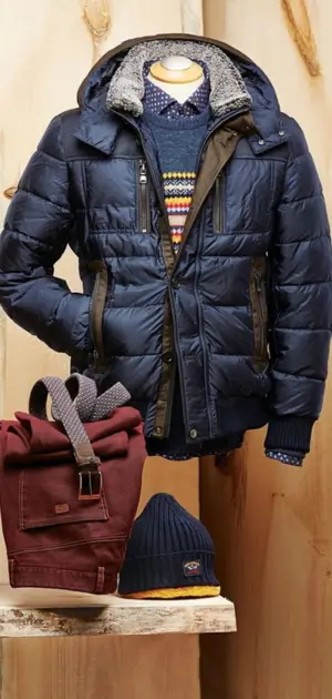 A navy polyester jacket with a colorful sweater, shirt, beanie, and maroon backpack.