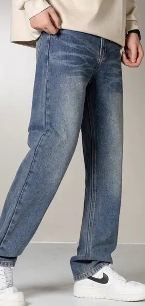 Relaxed blue polyester gym pants for men styled with a beige top and clean white sneakers.