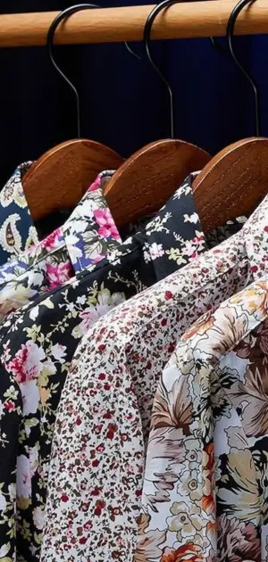 Men’s vintage men formal dress shirts with floral prints displayed on wooden hangers.