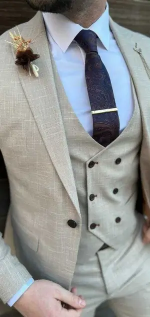 Linen wedding suits for men Beige linen three-piece formal suit paired with a paisley tie and lapel decor.
