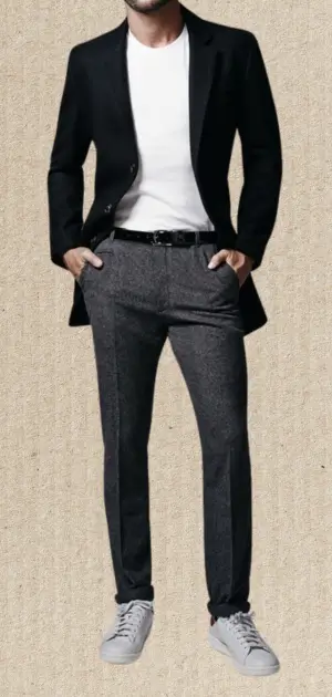 Man wearing a black blazer, gray trousers, and sneakers for a sports suits for men formal outfit.