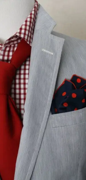 Light gray blazer featuring a red tie, checkered shirt, and polka-dot pocket square.