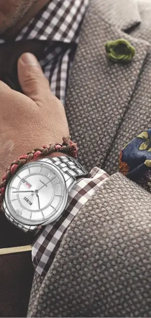 Close-up of a textured suit styled with a silver watch, pocket square, and lapel pin.