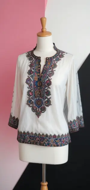 A white tunic blouse with vibrant embroidery around the neckline.