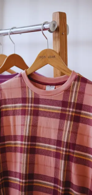 Woman choosing plaid t-shirts from clothing rack