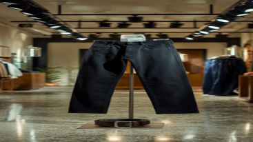 Black slim-fit jeans with a belt, displayed in a modern store