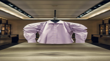A pastel pink formal shirt on a hanger in a modern retail environment.